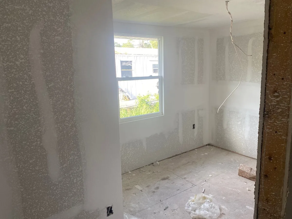 Unfinished room with drywall seams covered in joint compound and a single window.